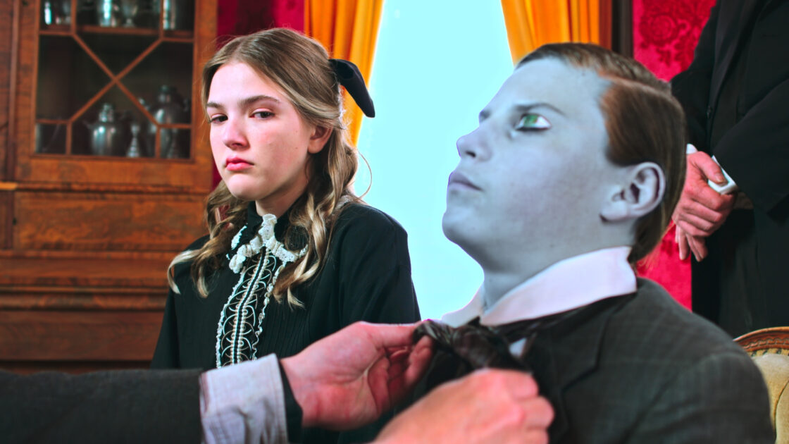 Ghost Town 2023 - A girl in the parlor sits with the dead body of a family member