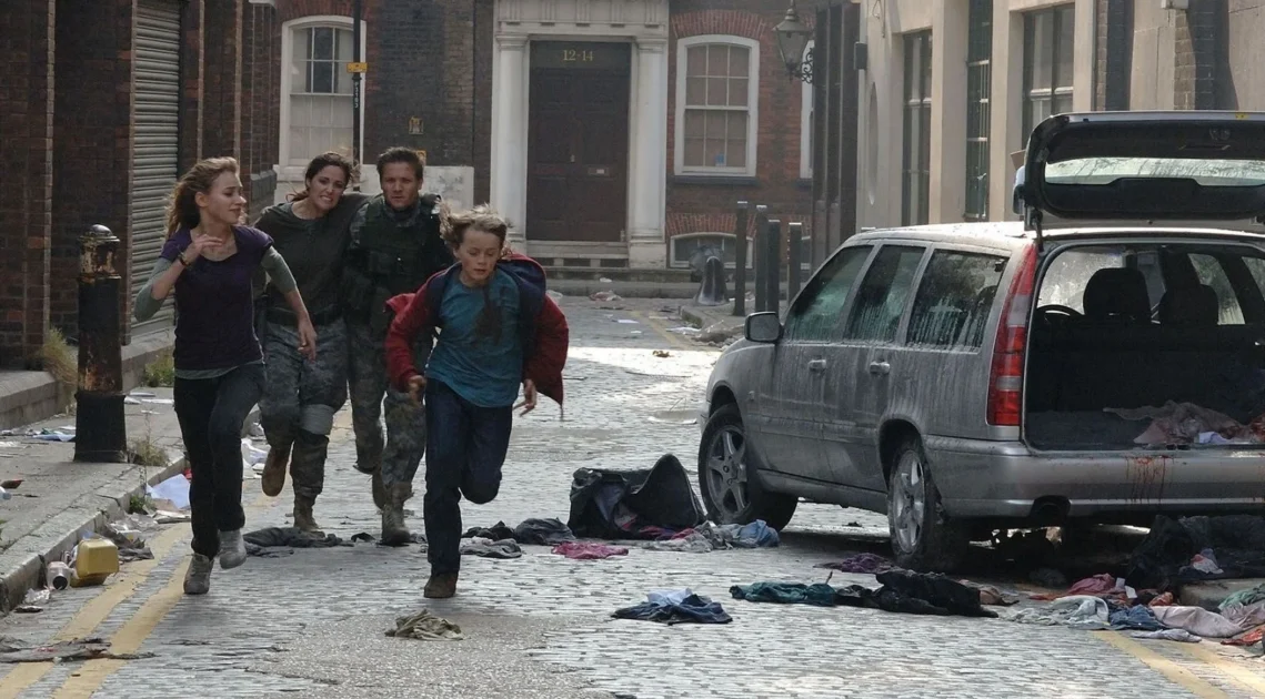 A group of four people running down a cluttered, cobblestone street in a panic.